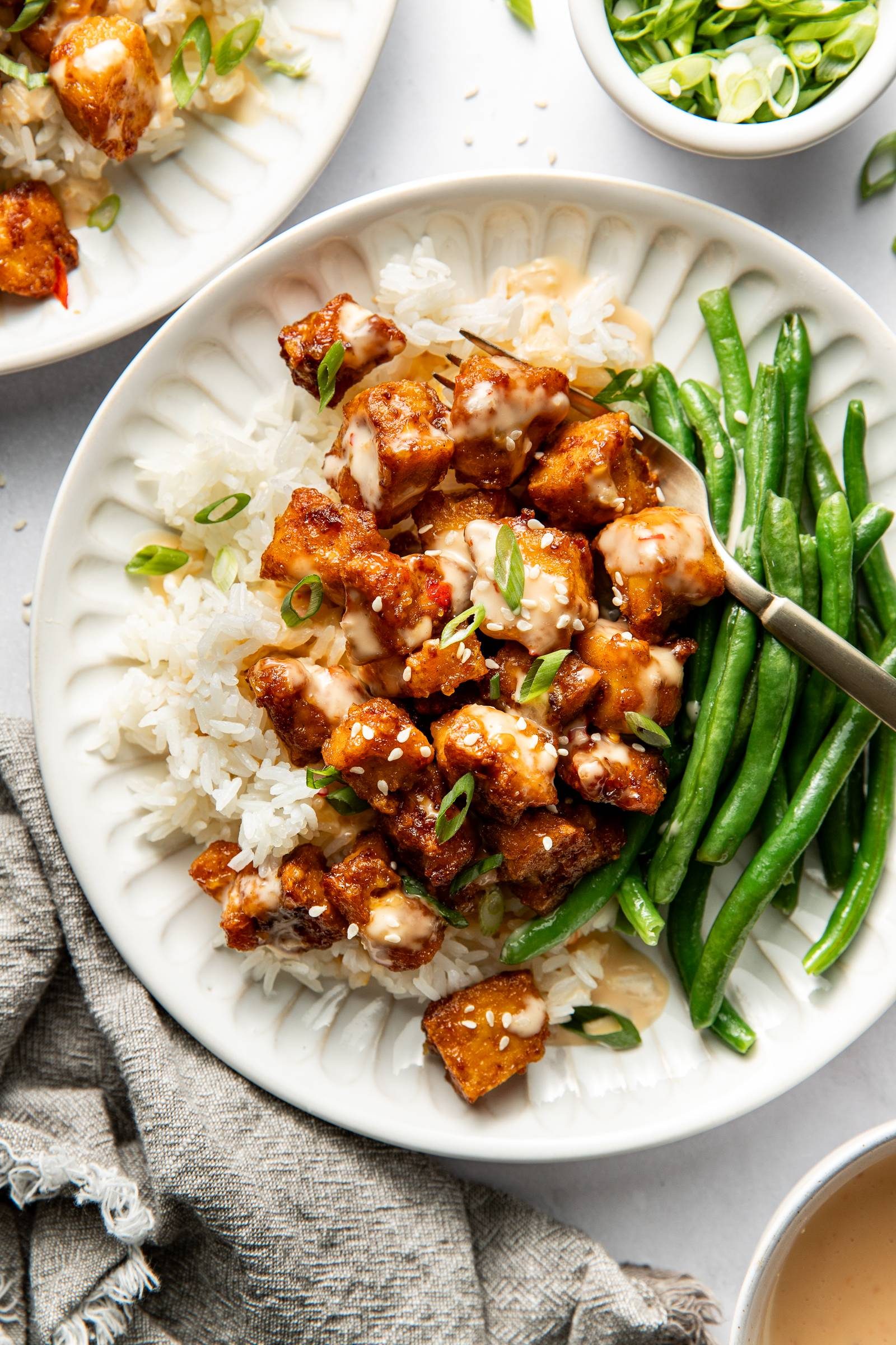 Bang bang tofu in a bowl with rice and green beans.