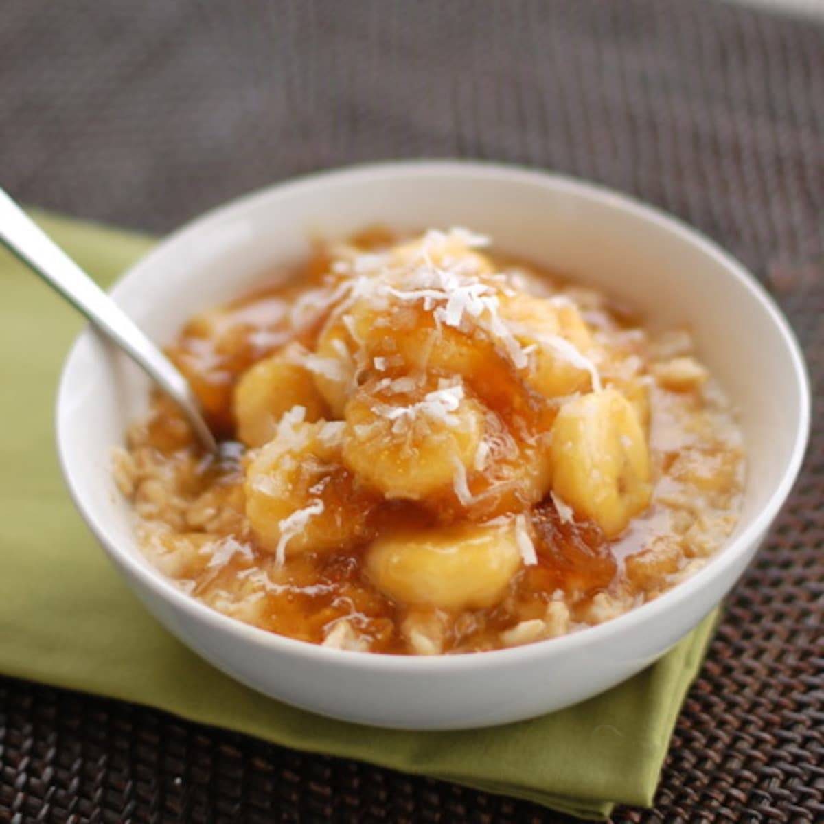 Caramelized banana and fig oatmeal in a bowl with a spoon on a green napkin.