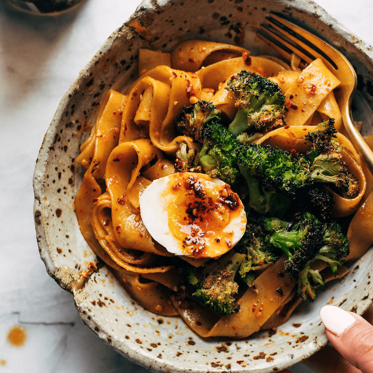 Chili garlic pappardelle in a bowl with broccoli and eggs.