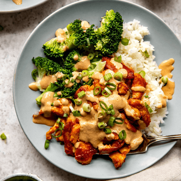 Red curry chicken in a bowl with rice and broccoli.