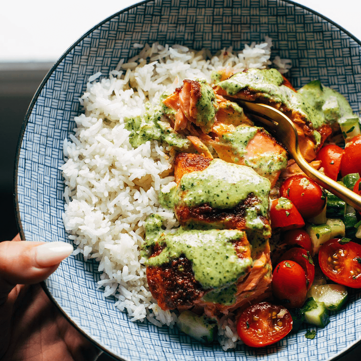 Salmon in a bowl with rice, tomato salad, and basil sauce.