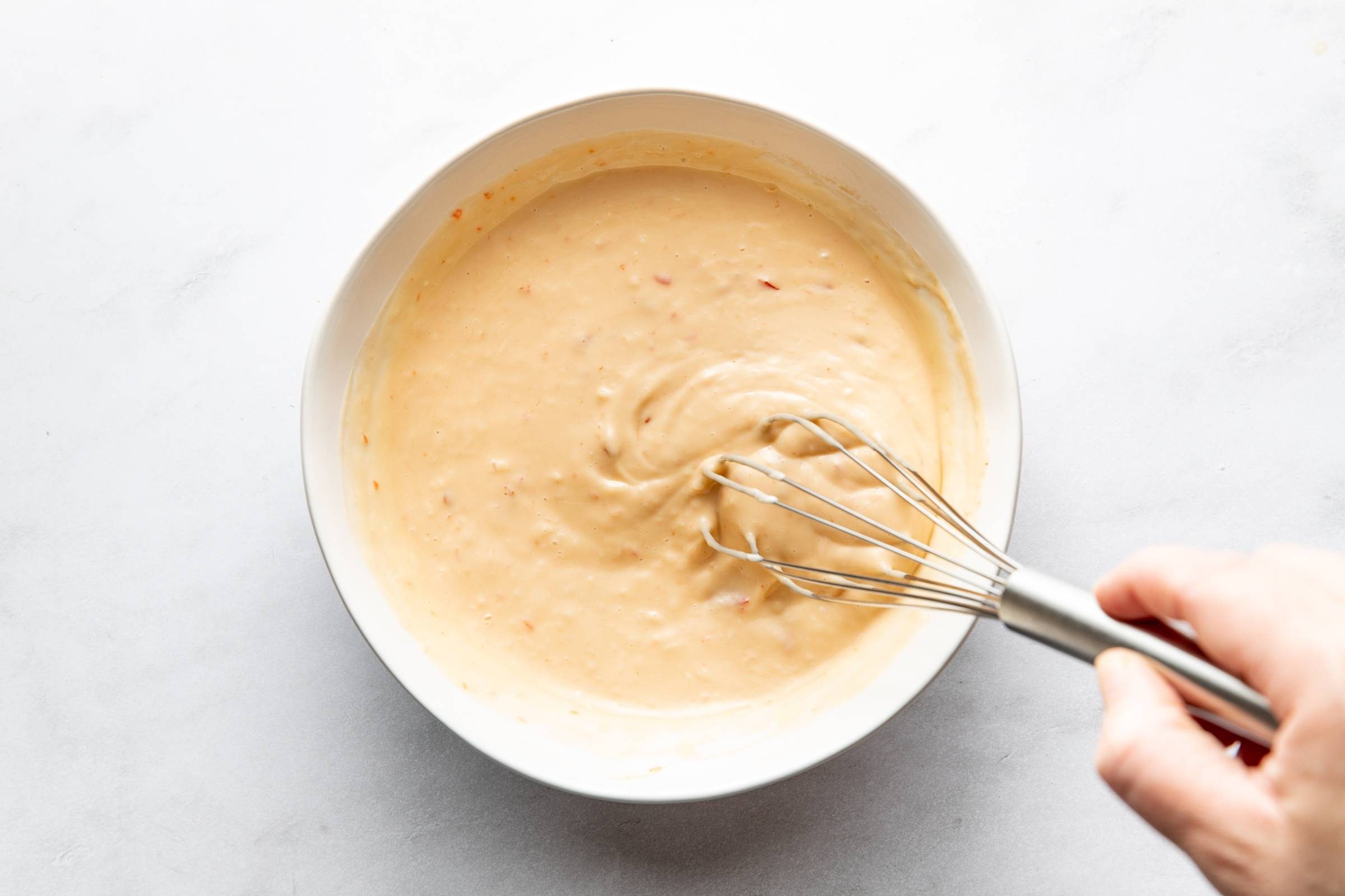 Whisking bang bang sauce in a bowl.