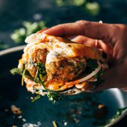 White hand holding a ginger chicken meatball sandwich